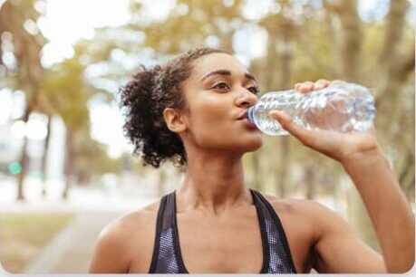 A woman drinks from a water bottle.