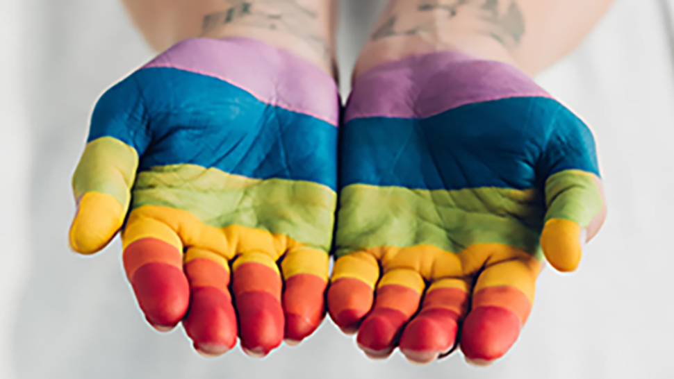Open hands are painted in rainbow colors
