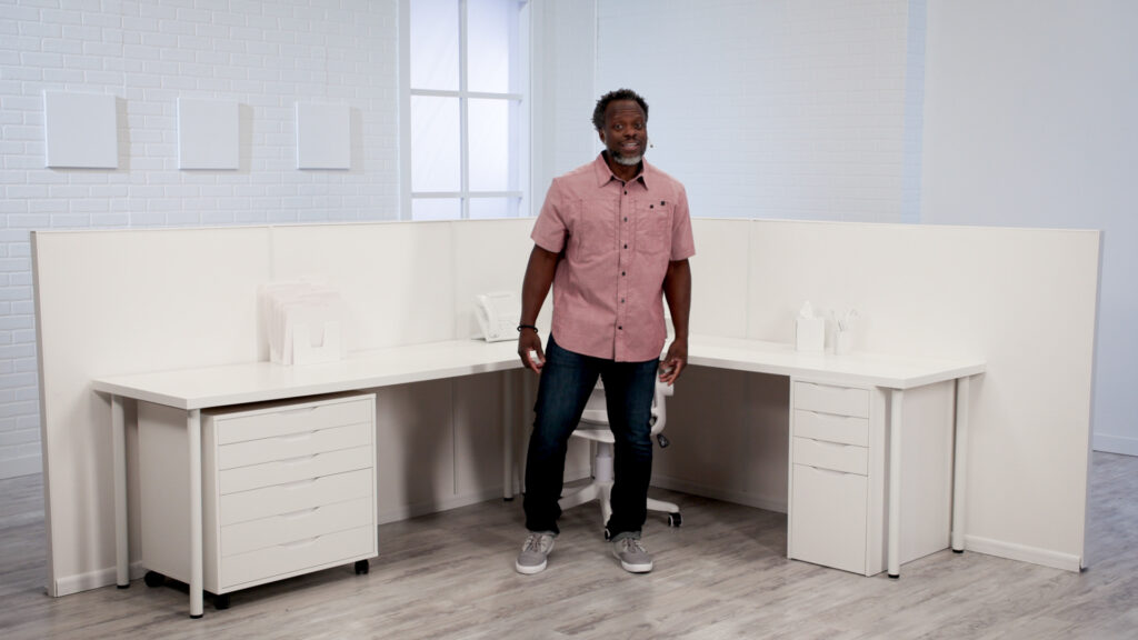 Wellbeats instructor Nate M. leads Reduce Tension while standing in front of a desk.