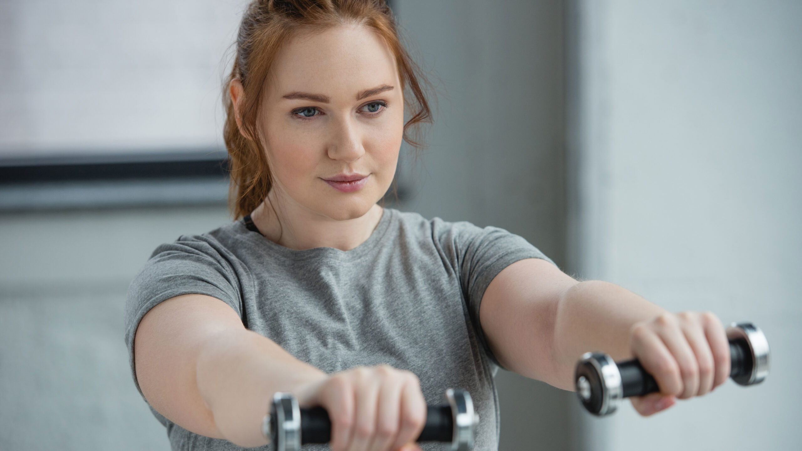 A woman works out holding dumbbells