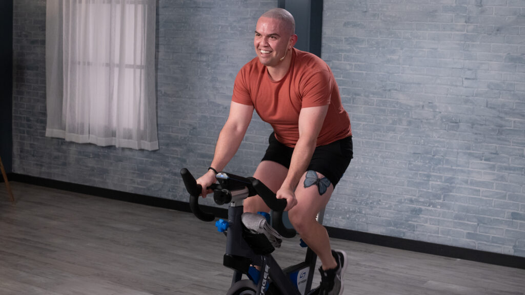 Wellbeats instructor Alejandro G. rides a stationary bicycle