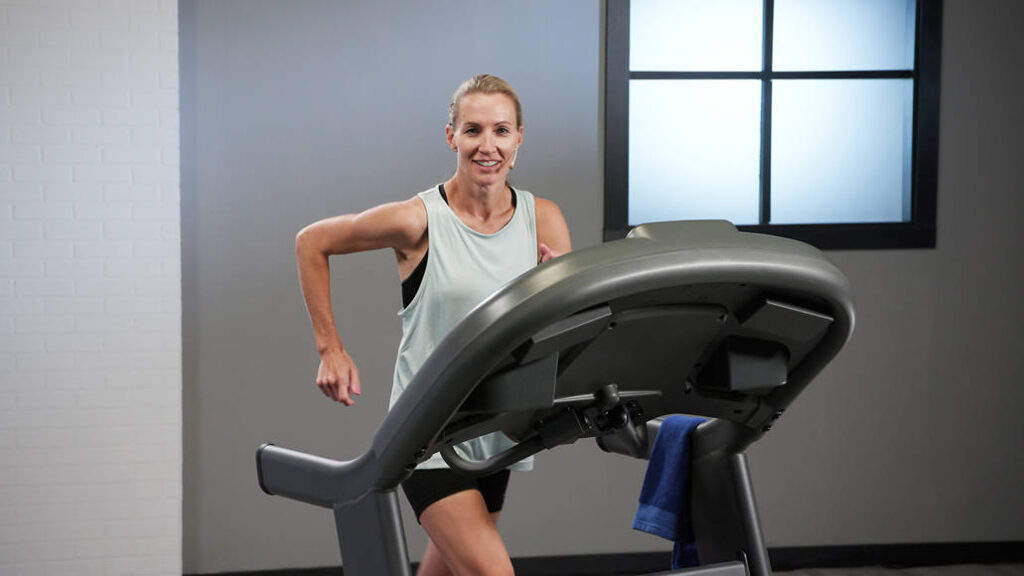 Wellbeats instructor Carrie T. smiles while running on a treadmill.