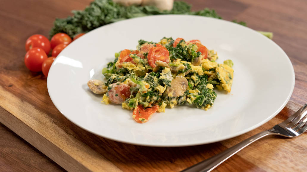 A veggie goat cheese scramble is plated on a table.