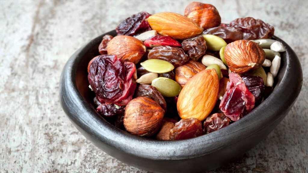 A bowl of nuts and raisins is positioned on a tabletop.